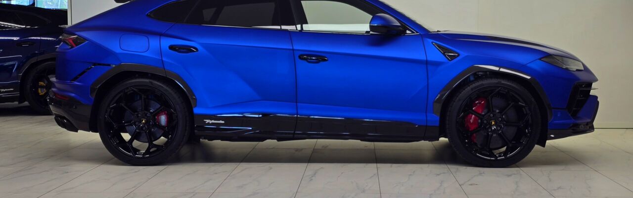 Lamborghini Urus azul visto de lado num estúdio claro